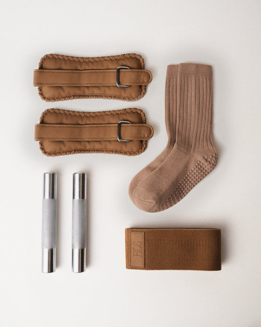 Set of Sand ankle weights, a sock, two steel hand weights, and sand color resistance band on a white background.