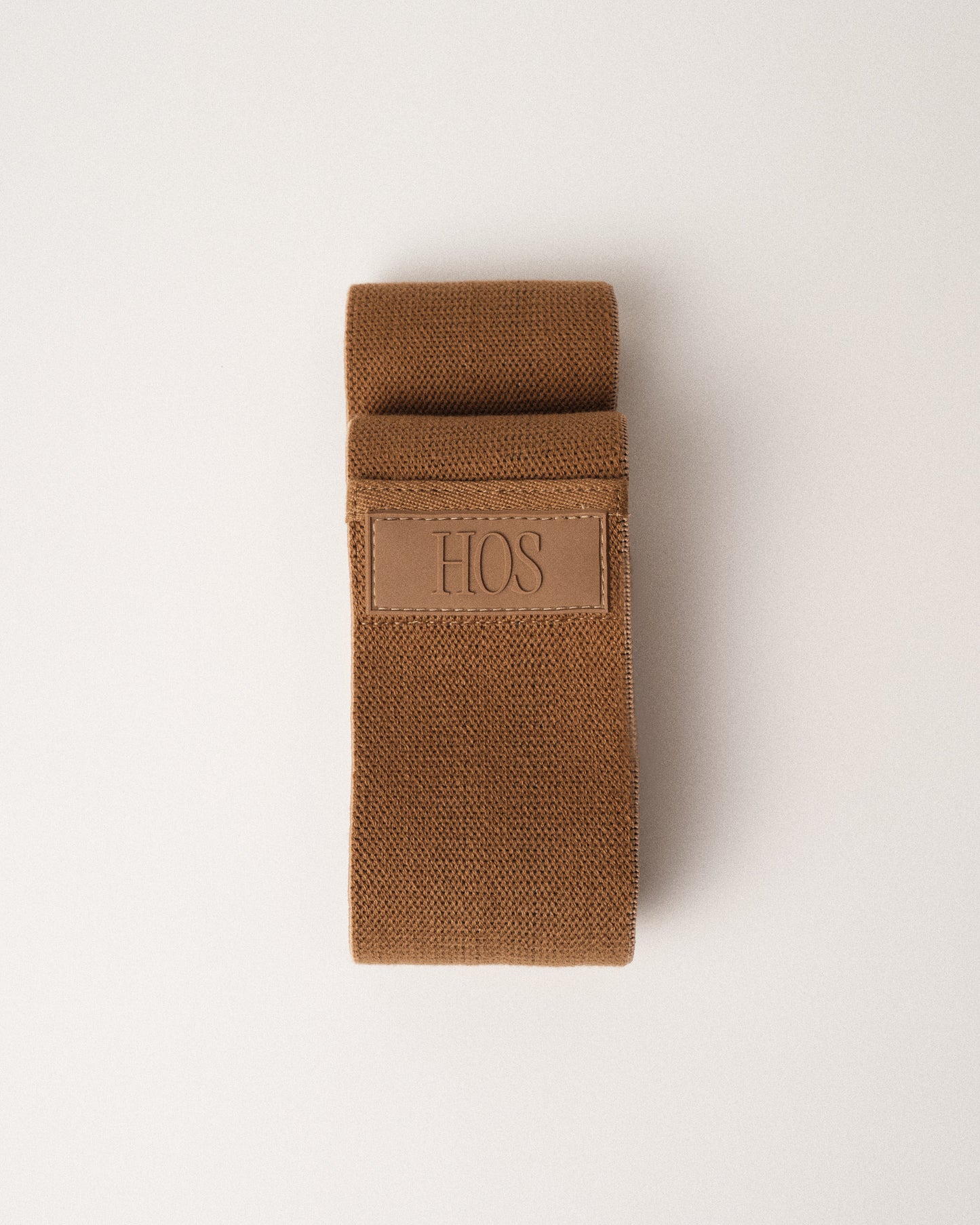 Sand color resistance band with HOS logo on a white background