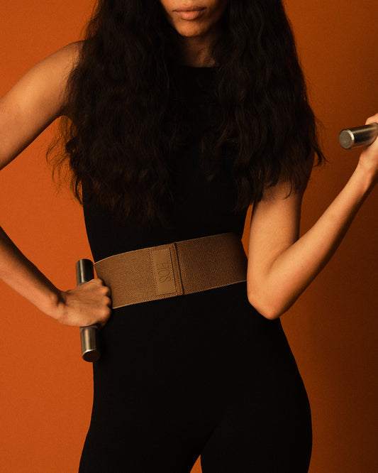 A model showing our steel hand weights and resistance band around her waist in a fashionable way with a red background
