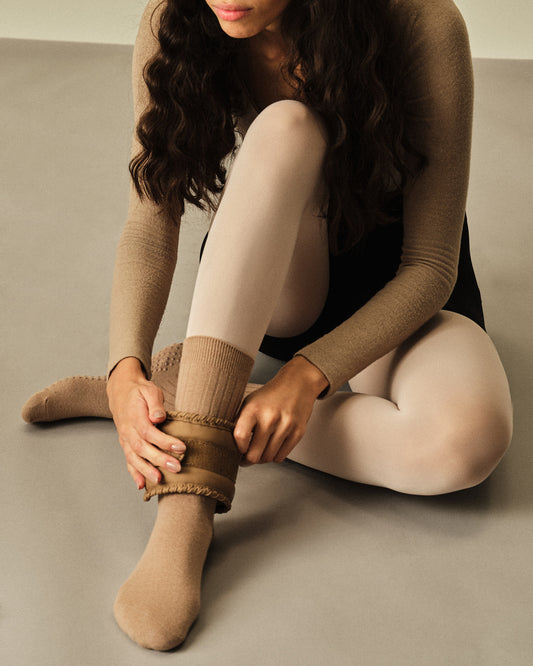 Our model wearing our grip socks and ankle weights sitting on a neutral background